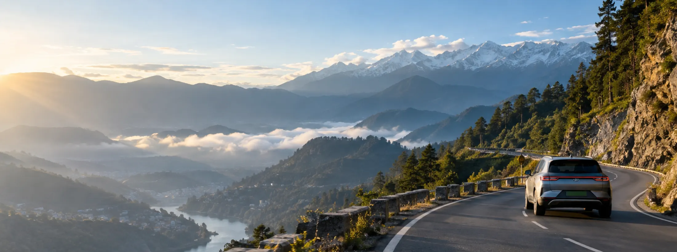 An electric car on an empty ghat road at sunrise, snow peaks and a valley of cloud below.